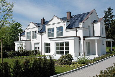 Exterior view of a white semi-detached house with a pointed roof and floor-to-ceiling windows