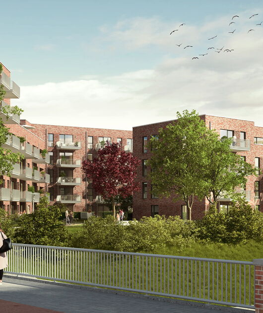 Eine moderne Backsteinwohnanlage mit mehreren Balkonen, umgeben von grünen Bäumen und Gras unter einem blauen Himmel mit fliegenden Vögeln. Eine Person geht entlang eines Weges mit einem Metallgeländer im Vordergrund.